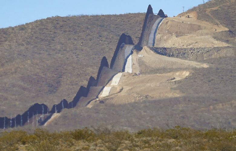 FILE – Newly erected border wall separating Mexico, left, and the United States, cuts through through the Sonoran Desert just west of the San Bernardino National Wildlife Refuge, Wednesday, Dec. 9, 2020, in Douglas, Ariz. Authorities are investigating the cause of death of a female migrant whose leg was entrapped while using a climbing harness and ended up hanging upside down off the border wall in eastern Arizona. U.S. Customs and Border Protection officials offered few details, but the local sheriff’s office said the woman was a 32-year-old Mexican who was attempting to cross the wall Monday, April 11, 2022 near Douglas, Arizona. Her name was not released. (AP Photo/Matt York,File) LA401 LA401