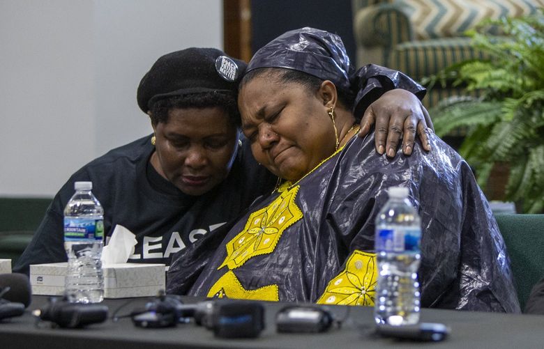 From left, Dorothy Sewe consoles Patrick Lyoya’s mother, Dorcas Lyoya, near Lyoya’s father, Peter Lyoya, during a news conference at the Renaissance Church of God in Christ Family Life Center in Grand Rapids, Mich. on Thursday, April 14, 2022. Civil rights attorney Ben Crump is representing the family of Patrick Lyoya, who was shot and killed by a GRPD officer on April 4. Sewe is a family friend and refugee from Kenya. (Cory Morse/The Grand Rapids Press via AP) MIGRA202 MIGRA202