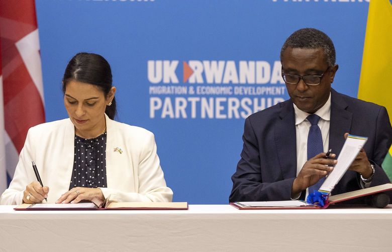 Britain’s Home Secretary Priti Patel, left, and Rwanda’s Minister of Foreign Affairs Vincent Biruta, right, sign what the two countries called an “economic development partnership” in Kigali, Rwanda Thursday, April 14, 2022. Britain’s Conservative government has struck a deal to send some asylum-seekers thousands of miles away to Rwanda, a move that British opposition politicians and refugee groups condemned as inhumane, unworkable and a waste of public money. (AP Photo/Muhizi Olivier) NAI118 NAI118