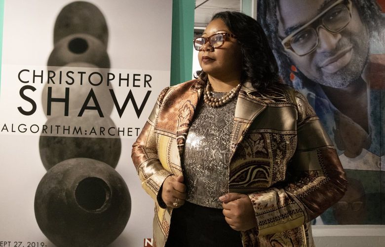 LaNesha DeBardelaben, Northwest African American Museum executive director, Tuesday, March 29, 2022 in Seattle, stands between two posters for exhibitions shut down by the pandemic. Both exhibits were video recorded before being taken down in March of 2020, and were then posted online.
 219942