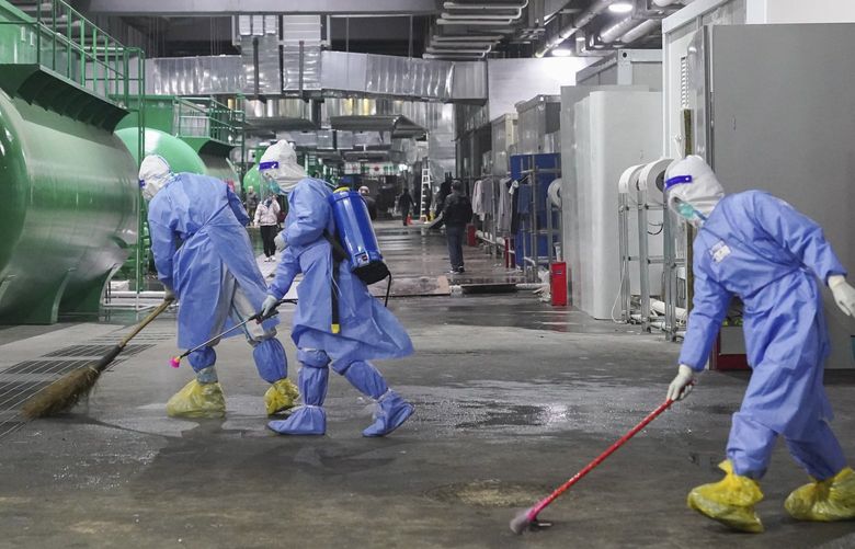 In this photo released by China’s Xinhua News Agency, workers clean and disinfect the floor of a makeshift hospital at the National Exhibition and Convention Center in Shanghai, Thursday, April 14, 2022. Anti-virus controls that shut down some of China’s biggest cities and fueled public irritation are spreading as infections rise, hurting a weak economy and prompting warnings of possible global shockwaves. (Ding Ting/Xinhua via AP) XIN802 XIN802