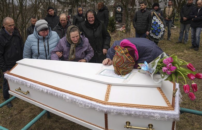 Liudmila Sumanchuk, center in black coat, cries during the funeral ceremony for her granddaughter Veronika Kuts in Lgiv village, Chernihiv region, Ukraine, Friday April 8, 2022. Veronika Kuts who was 12-year-old was killed during a Russian airstrike. (AP Photo/Evgeniy Maloletka) XB104 XB104