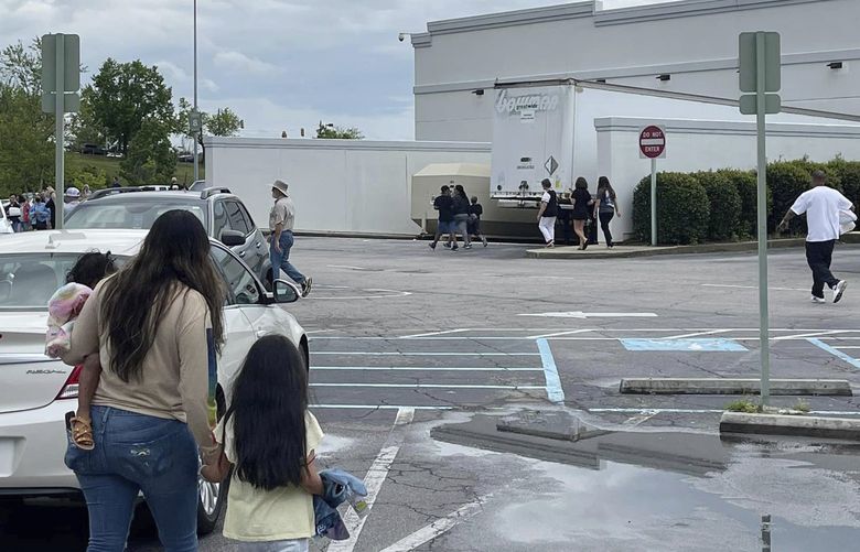 People walk through a parking lot at the Columbiana Centre mall in Columbia, S.C. on Saturday, April 16, 2022, as police investigate a shooting at the shopping center. (Justin Smith via AP) SCJS101 SCJS101