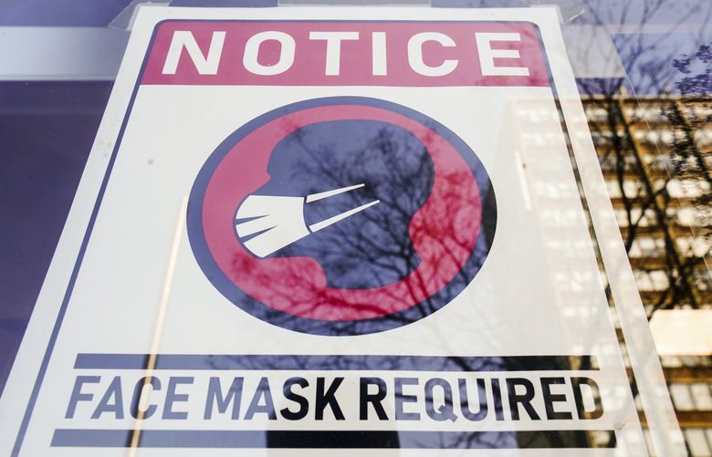 FILE – A sign requiring masks as a precaution against the spread of the coronavirus on a store front in Philadelphia, is seen Feb. 16, 2022. Philadelphia is reinstating its indoor mask mandate after reporting a sharp increase in coronavirus infections, Dr. Cheryl Bettigole, the city’s top health official, announced Monday, April 11, 2022. Confirmed COVID-19 cases have risen more than 50% in 10 days, the threshold at which the city’s guidelines call for people to wear masks indoors. (AP Photo/Matt Rourke, File)