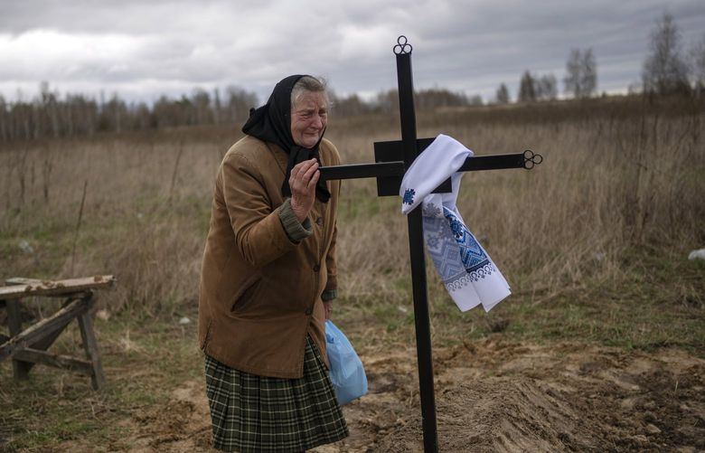 Nadiya Trubchaninova, 70, cries while holding the cross of her son Vadym, 48, who was killed by Russian soldiers last March 30 in Bucha, during his funeral in the cemetery of Mykulychi, on the outskirts of Kyiv, Ukraine, Saturday, April 16, 2022. After nine days since the discovery of Vadym’s corpse, finally Nadiya could have a proper funeral for him. This is not where Nadiya Trubchaninova thought she would find herself at 70 years of age, hitchhiking daily from her village to the shattered town of Bucha trying to bring her son’s body home for burial. (AP Photo/Rodrigo Abd) ABD102 ABD102