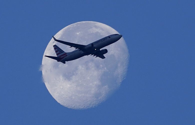 An American Airlines Boeing 737 flies past the moon as it heads to Orlando, Fla., after taking off from Miami International Airport on Tuesday. (AP Photo/Wilfredo Lee) 