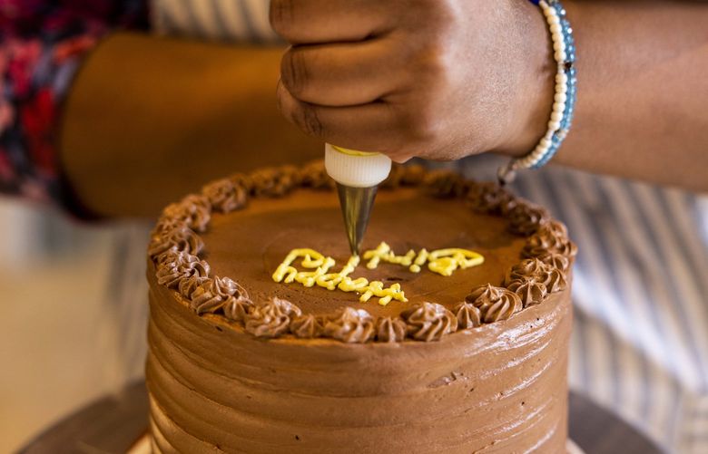 Baker Hana Yohannes decorates a chocolate birthday cake with a salted caramel filing for an order at Shikorina Pasteries on March 30, 2022.