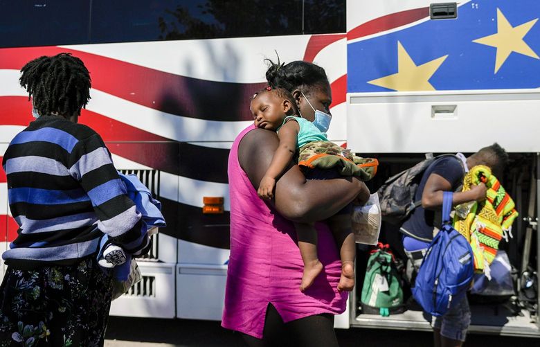 A young migrant sleeps on the shoulders of a woman as they prepare to board a bus toward Houston provided by a humanitarian organization after the migrants were released from U.S. Customs and Border Protection custody, Thursday, Sept. 23, 2021, in Del Rio, Texas. (AP Photo/Julio Cortez) TXJC126