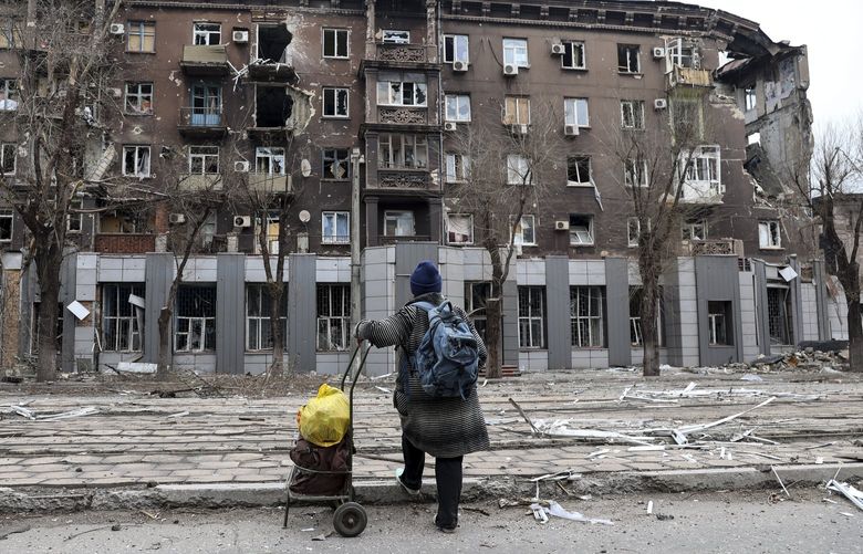 FILE – A local resident looks at a damaged during a heavy fighting apartment building near the Illich Iron & Steel Works Metallurgical Plant, the second largest metallurgical enterprise in Ukraine, in an area controlled by Russian-backed separatist forces in Mariupol, Ukraine, Saturday, April 16, 2022. Russian President Vladimir Putin ordered his forces not to storm the last remaining Ukrainian stronghold in the besieged city of Mariupol but to block it “so that not even a fly comes through.” Defense Minister Sergei Shoigu told Putin on Thursday that the sprawling Azovstal steel plant where Ukrainian forces were holed up was “securely blocked.” (AP Photo/Alexei Alexandrov) MHF101 MHF101
