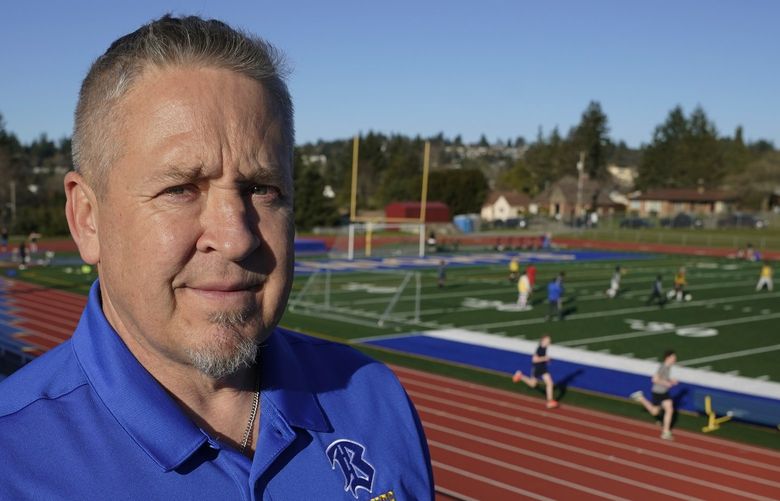 Joe Kennedy, a former assistant football coach at Bremerton High School in Bremerton, Wash., poses for a photo March 9, 2022, at the school’s football field. After losing his coaching job for refusing to stop kneeling in prayer with players and spectators on the field immediately after football games, Kennedy will take his arguments before the U.S. Supreme Court on Monday, April 25, 2022, saying the Bremerton School District violated his First Amendment rights by refusing to let him continue praying at midfield after games. (AP Photo/Ted S. Warren) WATW301 WATW301