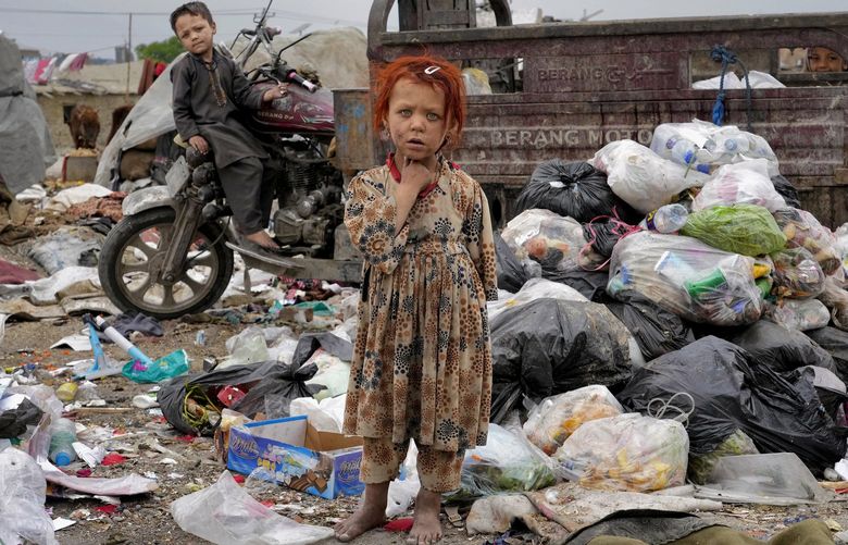 Two Afghan children  stand amid piles of garbage next to their home, in Kabul, Afghanistan, Monday, April 18, 2022. (AP Photo/Ebrahim Noroozi) ENO105 ENO105