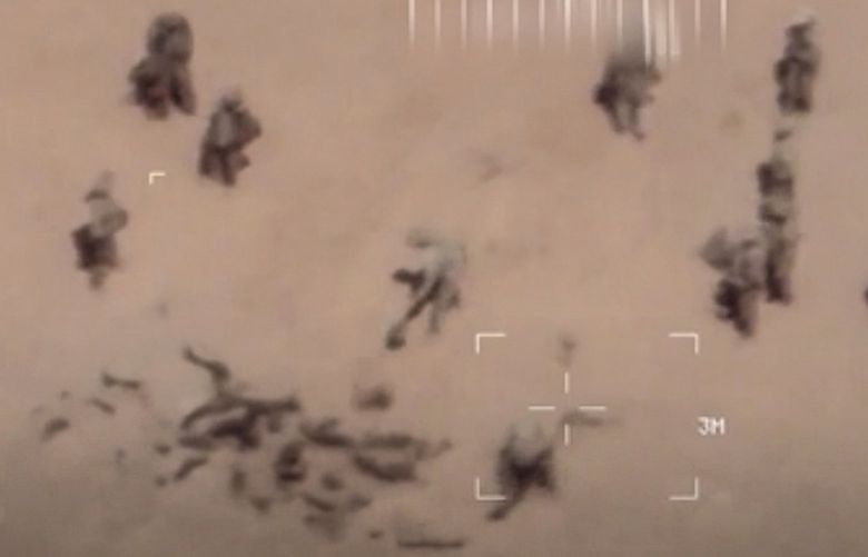 This image taken from a video shows armed men shoveling sand onto corpses in northern Mali. The French military says it has videos of Russian mercenaries burying bodies near an army base in northern Mali which it says is part of a smear campaign against the French who handed control of the base to Malian forces earlier this week. Aerial surveillance taken by the French military early Thursday and provided to The Associated Press show what appear to be 10 Caucasian soldiers covering approximately a dozen Malian bodies with sand near the Gossi military base, according to a French military officer who spoke on condition of anonymity because he was not authorized to speak to the press. (French Army via AP) MAL802 MAL802