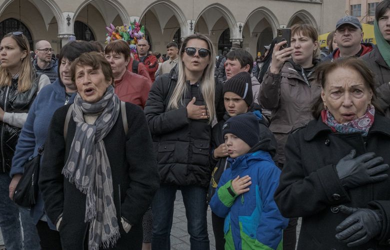FILE — Ukrainian refugees sing their national anthem during an antiwar protest in Krakow, Poland, on April 17, 2022. Warsaw gladly and proudly accepted 300,000 Ukrainians fleeing the war, but as the Polish capital braces for a new wave of refugees, its mayor warns that the city is “at capacity.” (Mauricio Lima/The New York Times) XNYT15 XNYT15