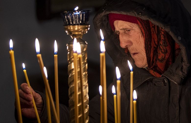 A woman lights candles during an Easter religious service celebrated at a church in Bucha, in the outskirts of Kyiv, on Sunday, April 24, 2022. (AP Photo/Emilio Morenatti) EM107 EM107