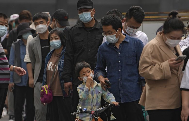 Residents and office workers wearing face masks line up for mass coronavirus testing outside a commercial office complex in Chaoyang district, Monday, April 25, 2022, in Beijing. Mass testing started Monday in the district, home to more than 3 million people in the Chinese capital, following a fresh COVID-19 outbreak. (AP Photo/Andy Wong) XAW109 XAW109