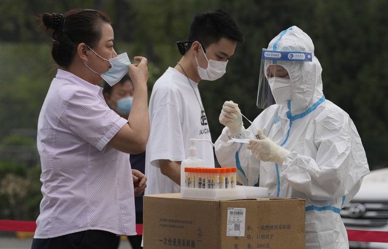 A medical worker collects a swab sample from a resident during mass testing for COVID-19 in Chaoyang district on Monday, April 25, 2022, in Beijing. China’s capital Beijing began testing millions of residents and shutting down residential and business districts Monday amid a new outbreak of COVID-19. (AP Photo/Ng Han Guan) XHG123 XHG123
