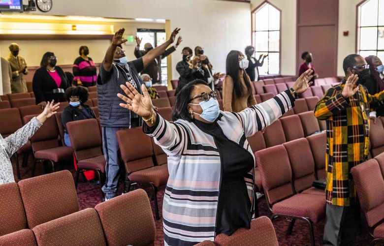Monette Hearn, center, who has been a congregant at Mount Calvary Christian Center Church of God in Christ for 10 years, sings with her community members during the praise service on Sunday, March 27. (Daniel Kim / The Seattle Times)