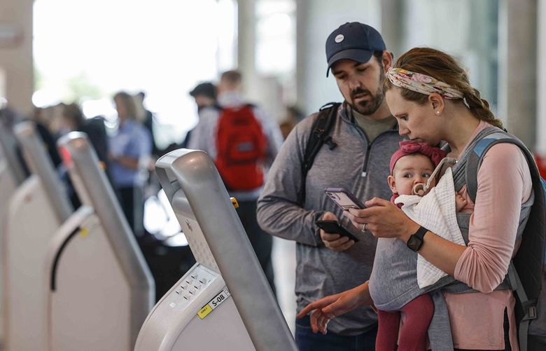 Cheryl Steifel, of Dallas, carrying her four-month-old daughter Emery, checks in for their flight to Nashville as her husband Zach Steifel watches on Tuesday, April 19, 2022, at Dallas Love Field Airport in Dallas, Texas. (Shafkat Anowar/Dallas Morning News/TNS) 