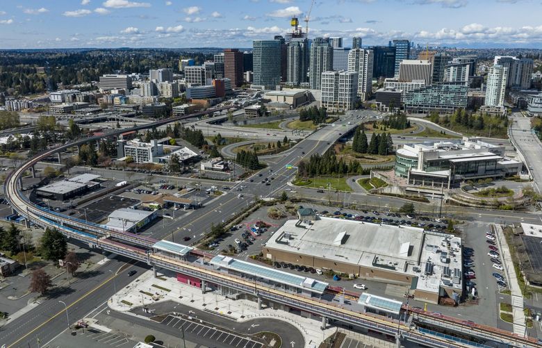 The elevated tracks for Sound Transit’s East Link Extension, which will connect the Northgate and Redmond Technology stations in 2023, are seen from the air, with downtown Bellevue in the background, Sunday, April 17, 2022. In the foreground is the future Wilburton station, situated just to the east of Whole Foods Market; its roof seen at lower right.