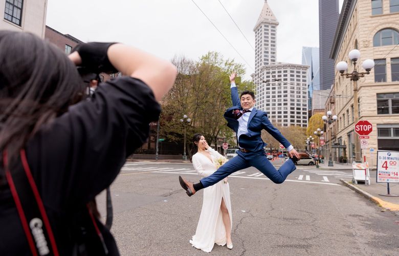 Photographer Xuefang Zhao CQ, with SFV Studio, from left, takes wedding portraits of Xiaolei Xu and Wenzhi Zhao in Seattle’s Pioneer Square neighborhood Tuesday, April 26, 2022.  Xu and Zhao married at Kerry Park earlier in the day, surrounded by about 15 friends and family. “I was crying,” says Zhao. The couple was introduced to each other by friends about three years ago. 
LO 220236