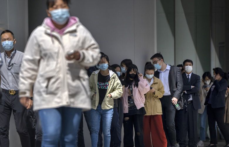 People wearing face masks stand in line for coronavirus tests at an office building in the Dongcheng district of Beijing, Tuesday, April 26, 2022. Beijing will conduct mass testing of most of its 21 million people, authorities announced Monday, as a new COVID-19 outbreak sparked stockpiling of food by residents worried about the possibility of a Shanghai-style lockdown. (AP Photo/Mark Schiefelbein) XMAS111 XMAS111