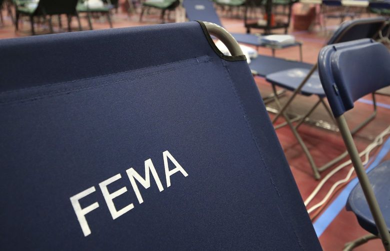 FILE – A portable cot, with the Federal Emergency Management Agency logo FEMA printed on the backrest, and other cots line the basketball court at a makeshift medical facility in a gymnasium at Southern New Hampshire University in Manchester, N.H., March 24, 2020. FEMA may have been double-billed for the funerals of hundreds of people who died of COVID-19, the Government Accountability Office said in a new report Wednesday, April 27, 2022. (AP Photo/Charles Krupa, File) WX106 WX106