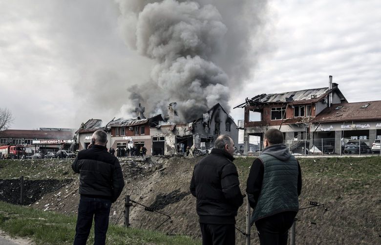 FILE – Local residents look on as firefighters battle a blaze at the scene of a missile strike in Lviv, Ukraine, on Monday, April 18, 2022. Fear is ricocheting from Washington to European capitals that the Ukraine war is quickly running the risk of slipping into a wider war – spreading to neighboring states, to NATO countries suddenly facing a Russian cutoff of gas, to cyberspace and to a direct effort by Washington and Moscow to sap each other’s power. (Finbarr O’Reilly/The New York Times) XNYT168 XNYT168