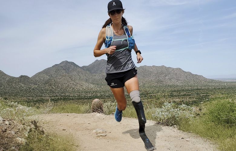 In this image provided by Edwin Broersma, marathoner Jacky Hunt-Broersma trains on Aug. 28, 2021 at San Tan Mountain Regional Park, in San Tan Valley, Az. Hunt-Broersma lost her left leg below the knee to a rare form of cancer, but she hasn’t let that stop her and is trying to cover the classic 26.2-mile marathon distance at least 102 times in 102 days, which would set a new world record. The Boston Marathon on April 18 is expected to be No. 92 in her streak. (Edwin Broersma via AP) BX501 BX501
