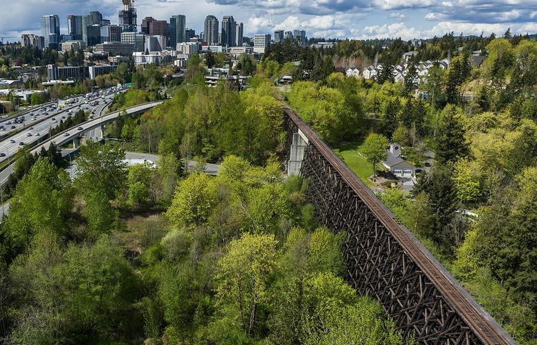 The Willburton trestle bridge is seen from the air with downtown Bellevue in the background, Wednesday, April 27, 2022. The bridge, part of the Eastrail bike lane that is due to receive $29 million from the legislature in this year’s transportation package, is going to need much of that money for retrofitting and expansion. At left is Interstate 405.
