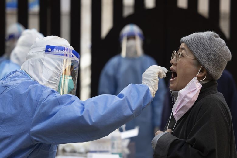 2022 年 4 月 4 日星期一，中国东部安徽省的一名医务人员在上海市黄浦区的一个社区采集居民的拭子样本进行核酸检测。中国已从全国各地派出 10,000 多名医务人员前往上海，包括 2,000 名军事医务人员，因为它正在努力遏制在中国最大城市迅速蔓延的 COVID-19 疫情。 （金立旺/美联社）