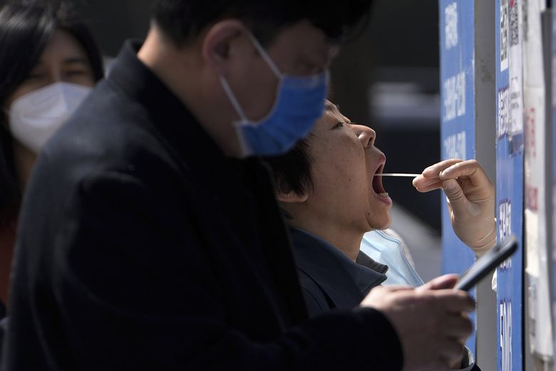 周二，北京的一个新冠病毒检测点，居民排队领取咽拭子。 中国已从全国各地派出 10,000 多名卫生工作者前往上海，其中包括 2,000 名军事医务人员，以努力遏制在中国最大城市迅速蔓延的 COVID-19 疫情。 （安迪黄/美联社）