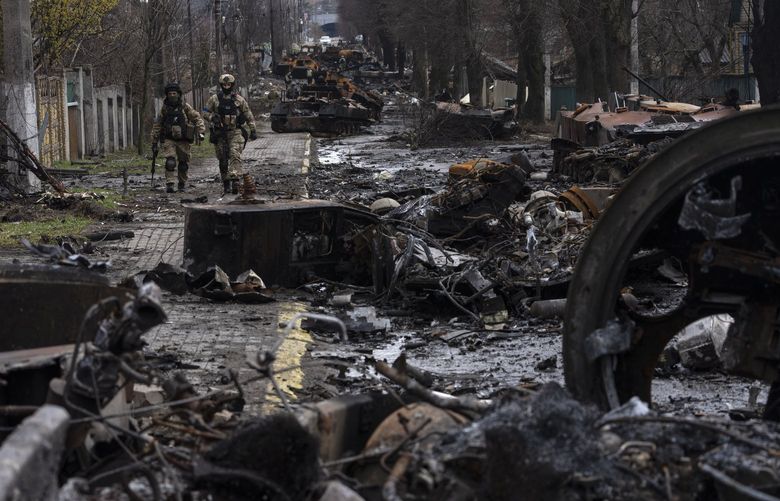 Soldiers walk amid destroyed Russian tanks in Bucha, in the outskirts of Kyiv, Ukraine, Sunday, April 3, 2022. Ukrainian troops are finding brutalized bodies and widespread destruction in the suburbs of Kyiv, sparking new calls for a war crimes investigation and sanctions against Russia. (AP Photo/Rodrigo Abd) ABD109 ABD109