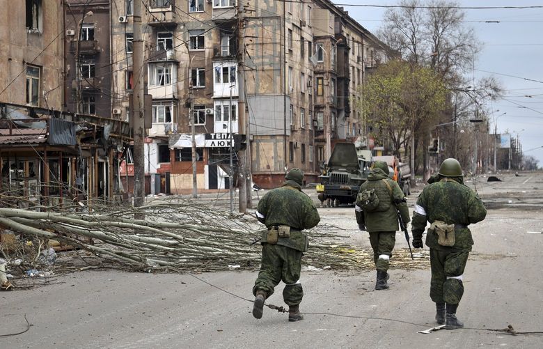 Servicemen of Donetsk People’s Republic militia walk past damaged apartment buildings near the Illich Iron & Steel Works Metallurgical Plant, the second largest metallurgical enterprise in Ukraine, in an area controlled by Russian-backed separatist forces in Mariupol, Ukraine, Saturday, April 16, 2022. Mariupol, a strategic port on the Sea of Azov, has been besieged by Russian troops and forces from self-proclaimed separatist areas in eastern Ukraine for more than six weeks. (AP Photo/Alexei Alexandrov) MAR125 MAR125