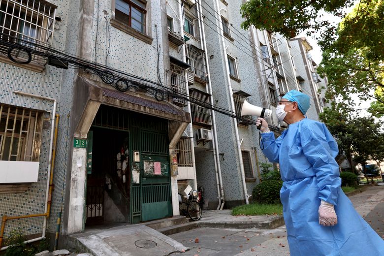 周二，在中国上海的一栋公寓楼里，一名志愿者使用扩音器与居民交谈。 政府周三表示，在 COVID-19 爆发期间，上海已释放超过 6,000 名医学观察者，但进一步放松对中国最大城市的封锁的举措似乎停滞不前。 （陈建利/新华社通过美联社）