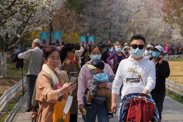 2022 年 4 月 8 日星期五，北京，春节期间，戴着口罩的游客在玉渊潭公园欣赏樱花。 上海的三名地方官员因对中国最大城市 COVID-19 疫情反应迟缓而被解雇，当地居民抱怨严酷的封锁条件导致食品和基本必需品短缺。 （美联社照片/安迪黄）