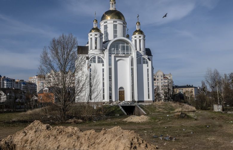 FILE — A mass grave on the grounds of the Church of St. Andrews in Bucha, Ukraine, April 7, 2022. Ukrainian authorities have now released names and photos of Russian soldiers they accuse of abuses against civilians during their occupation of Bucha. (Daniel Berehulak/The New York Times) XNYT140 XNYT140