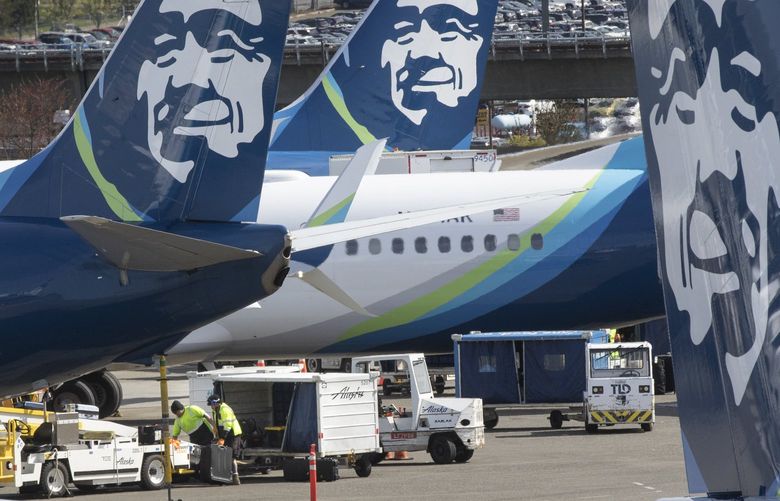 Baggage handlers load luggage onto an Alaska Airlines jet shortly before takeoff at Seattle-Tacoma International Airport in SeaTac Thursday, April 7, 2022.  Expansion plans at Alaska Airlines have been hit by the reality of staff shortages and travel chaos. 220071