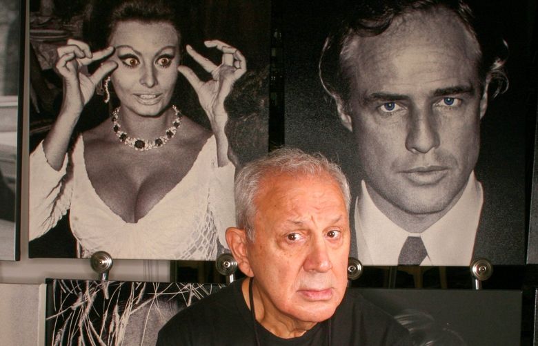 FILE — Ron Galella and a few of his celebrity photos at his home in Montville, N.J., Sept. 15, 2006. Galella, the freelance photographer who relentlessly pursued Jacqueline Kennedy Onassis until a judge barred him from taking her picture, who pestered Marlon Brando until Brando broke his jaw, and who helped define today’s boundary-challenged culture of celebrity, died on Saturday, April 30, 2022, at his home in Montville, N.J. He was 91. (Fred R. Conrad/The New York Times) XNYT262