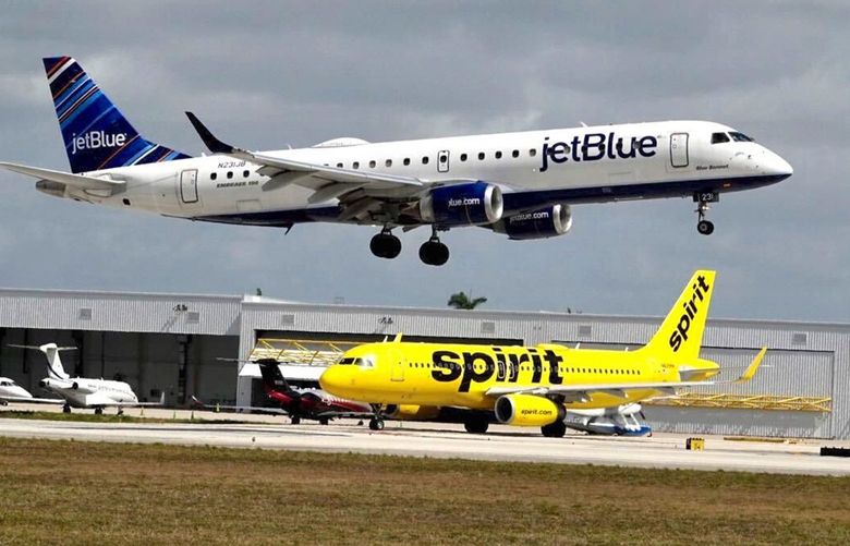 A JetBlue airliner lands past a Spirit Airlines jet on taxi way at Fort Lauderdale Hollywood International Airport on Monday, April 25, 2022. (Joe Cavaretta/Sun Sentinel/TNS) 