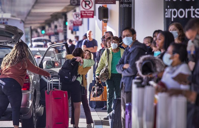 An air travel passenger is hugged while being picked up amid a long line of travelers awaiting rides after arriving at Los Angeles International Airport terminal 1 for the Thanksgiving holiday in Los Angeles on Nov. 23, 2021. (Allen J. Schaben/Los Angeles Times/TNS) 46566236W 46566236W