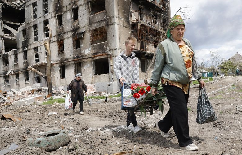 Women walk past a destroyed apartment building in Mariupol, in territory under the government of the Donetsk People’s Republic, eastern Ukraine, Monday, May 2, 2022. (AP Photo/Alexei Alexandrov) MAR103 MAR103