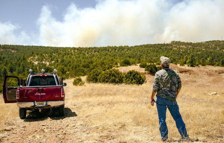 A man watches as smoke from the Calf Canyon/Hermits Peak fire rises above a ridge near Las Vegas, N.M., on Tuesday, May 3, 2022. While no lives have been lost, the Calf Canyon/Hermits Peak fire has destroyed at least 172 homes, forced many families to evacuate and remains just 20 percent contained. (Adria Malcolm/The New York Times) XNYT174