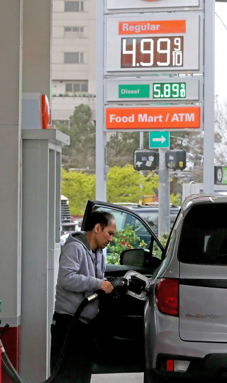 Gas prices are hovering near $5 a gallon in King County. Diesel fuel, in green, is even higher. Tim Temmer is at the Union gas station on Broad Street and Denny Way. (Greg Gilbert / The Seattle Times)