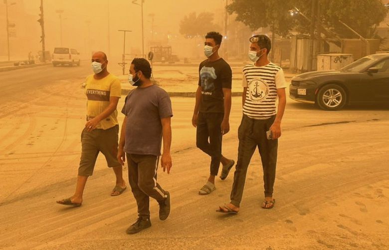 People walk through a sand storm in Baghdad, Iraq, Thursday, May 5, 2022. Hundreds of Iraqis with respiratory problems went to hospitals with flights suspended on Thursday as Iraqis awoke to a fifth sand storm to engulf the country within a month. (AP Photo/Ali Abdul Hassan) DV102 DV102