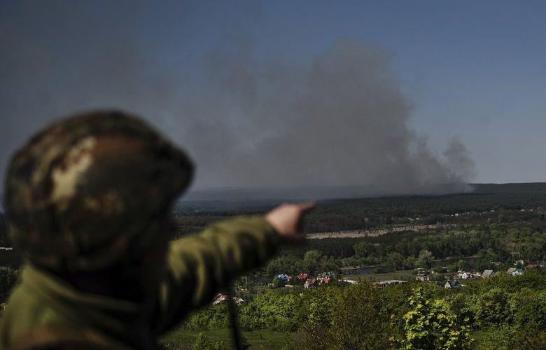 A Ukrainian soldier points out smoke from shelling near the frontline in the Kramatorsk region of Ukraine, May 5, 2022. Russian fighter jets launched three airstrikes on the eastern Ukrainian city of Kramatorsk on Thursday morning, injuring at least 26 people, and gutting a large apartment complex and a store selling bras and underwear. (Lynsey Addario/The New York Times) — NO SALES XNYT28 XNYT28