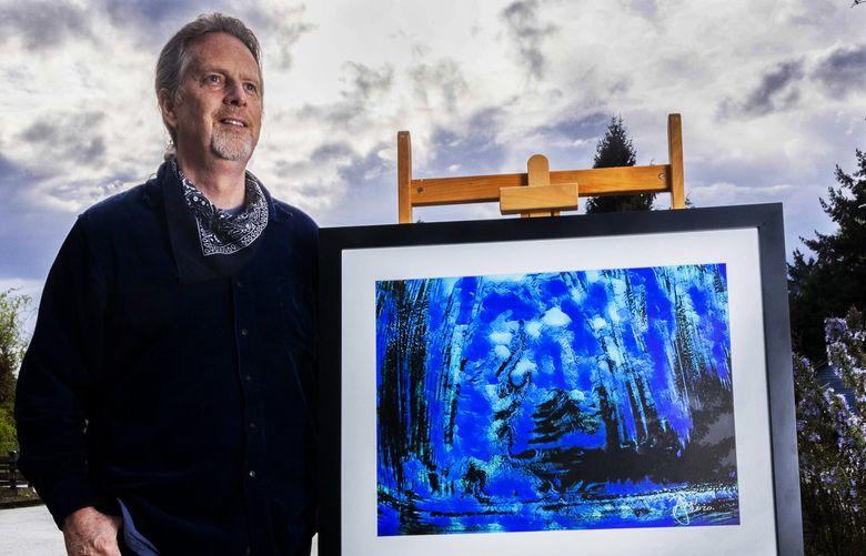 Artist Flynn stands outside of his home with his art work “Blue Forest” at his rental home in Lynnwood on April 27, 2022.
