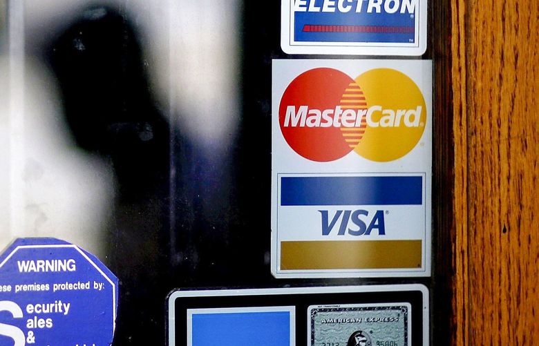 A pedestrian walks past credit card logos posted on a downtown storefront in Atlanta in this 2012 file photo.