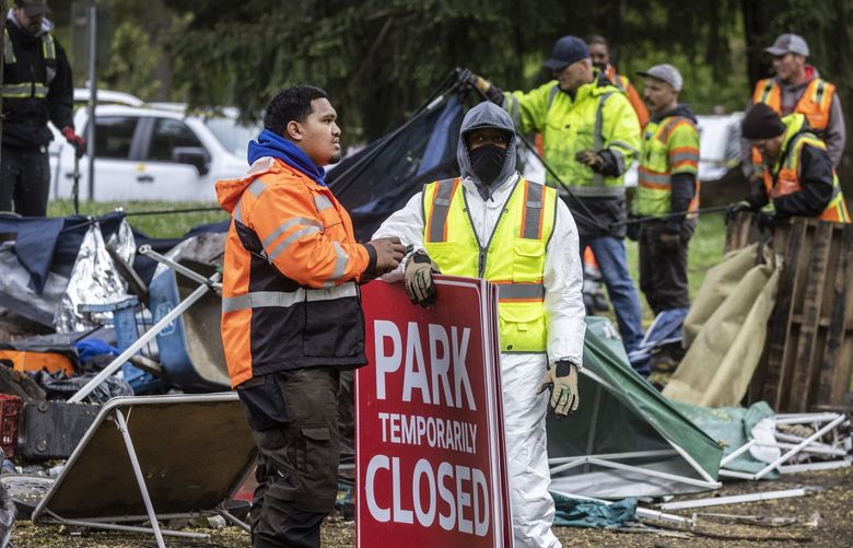 Tuesday, May 10, 2022.   Seattle Parks employees and contractors start prepare to shut down Woodland Park near the lawn bowling center as work clearing the homeless encampment continues in the backround.   220345