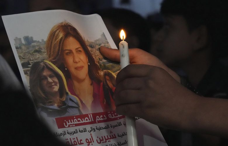 Palestinian holds a light candle and a picture of slain Al Jazeera journalist Shireen Abu Akleh, to condemn her killing, in front of the office of Al Jazeera network, in Gaza City, Wednesday, May 11, 2022. Abu Akleh was shot and killed while covering an Israeli raid in the occupied West Bank town of Jenin early Wednesday. (AP Photo/Adel Hana) XAH108 XAH108