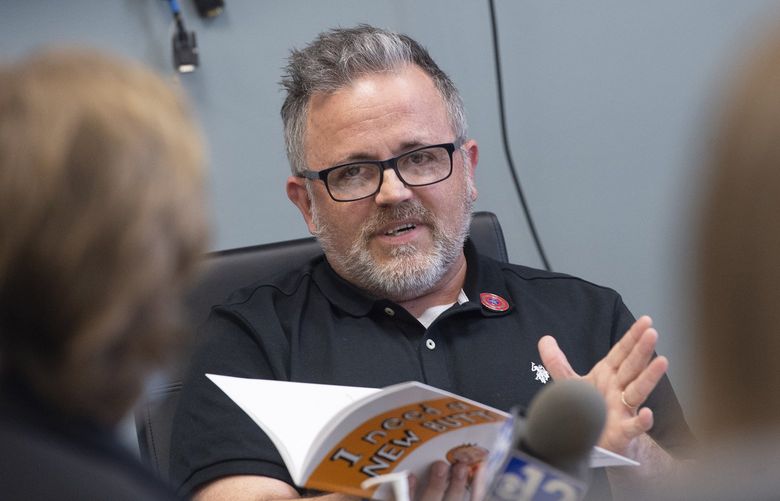 FILE – Toby Price, a former assistant principal at Gary Road Elementary School in Byram, Miss., testifies during an appeal hearing at the Hinds County Schools administration building in Raymond, Miss., Monday, March 28, 2022, regarding his dismissal after reading the children’s book he’s holding, “I Need a New Butt!” by Dawn McMillan. Price told the Clarion Ledger he received a 12-page order Monday, May 11, 2022, showing the Hinds County School Board had voted 2-1 to uphold the superintendent’s decision to fire him in March. He was assistant principal at Gary Road Elementary in the Jackson suburb of Byram.(Barbara Gauntt/The Clarion-Ledger via AP, File) MSJAD201 MSJAD201